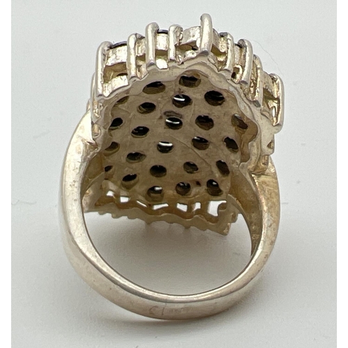 1089 - A large silver & stone set statement cocktail style dress ring. Top of ring set with 29 round cut bl... 