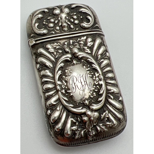 1132 - A Victorian silver vesta case with decorative floral and scroll detail shown in relief. Hinged lid, ... 