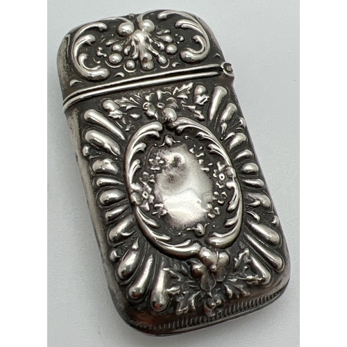 1132 - A Victorian silver vesta case with decorative floral and scroll detail shown in relief. Hinged lid, ... 