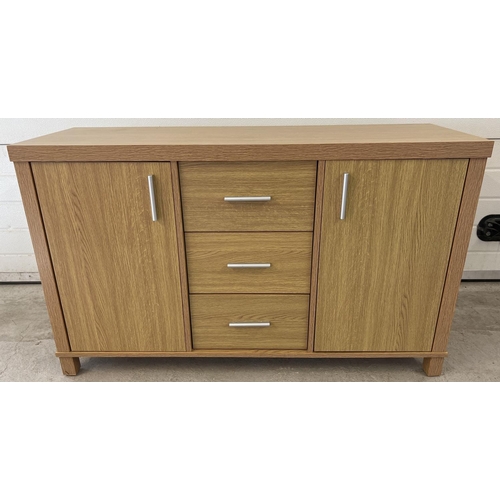 1296 - A modern light wood effect, sideboard with 2 cupboards and 3 central drawers. Long silver coloured h... 