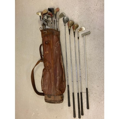 1239 - A vintage leather golf club bag by Spalding together with a collection of vintage woods, putters and... 