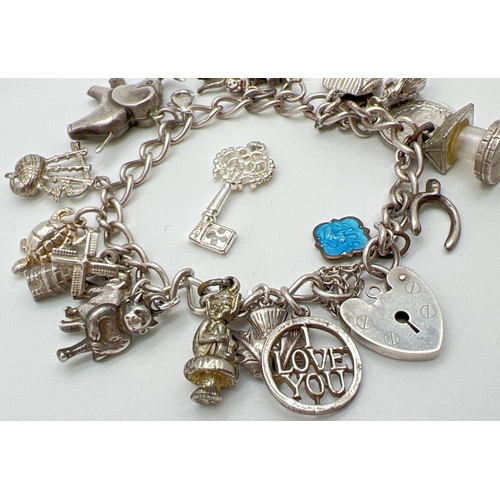 1016 - A vintage charm bracelet with padlock clasp and safety chain. With 19 silver and white metal charms ... 