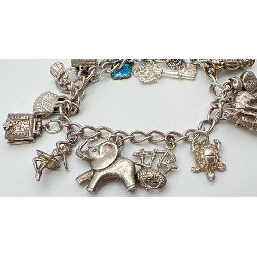 1016 - A vintage charm bracelet with padlock clasp and safety chain. With 19 silver and white metal charms ... 