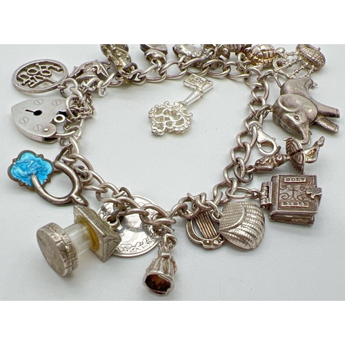 1016 - A vintage charm bracelet with padlock clasp and safety chain. With 19 silver and white metal charms ... 