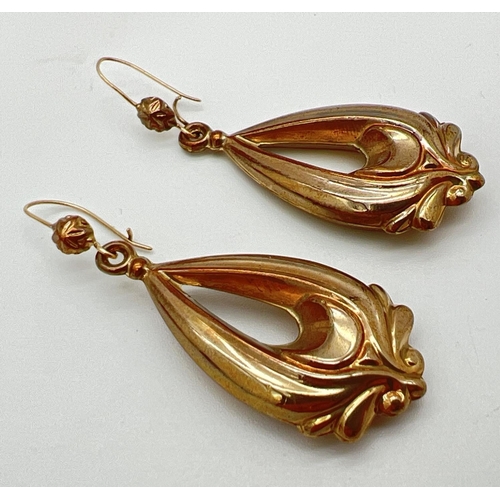 1042 - A pair of yellow gold drop style earrings with scroll detail and hooked posts. Approx. 5cm long incl... 