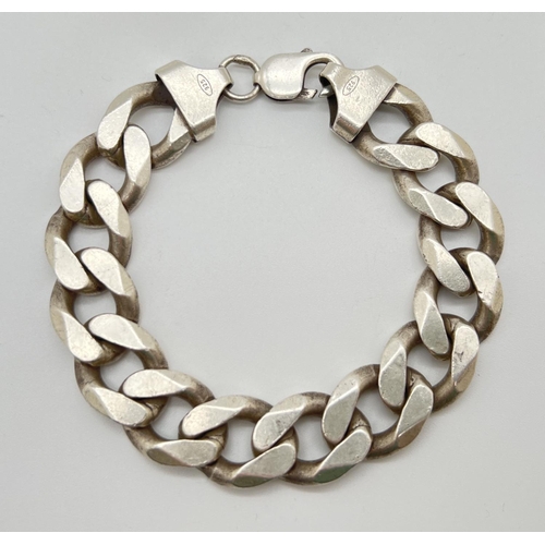 1045 - A heavy silver 9 inch large curb link bracelet with lobster clasp. Silver marks to fixings and clasp... 