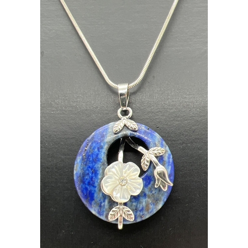 1063 - A modern design circular Lapis Lazuli pendant with floral mother of pearl set overlay on a 24 inch f... 