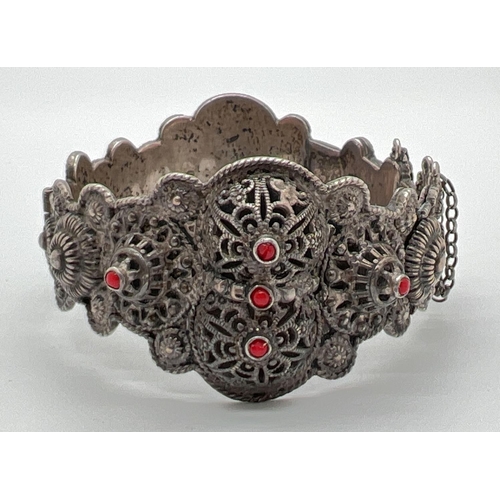 1069 - A decorative ethnic style pierced work bracelet with small red glass bead detail. Sliding key fasten... 