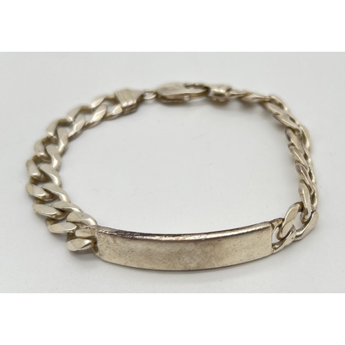 1071 - A heavy silver curb chain identity bracelet with empty cartouche. Approx 8.5 inches long. Total weig... 