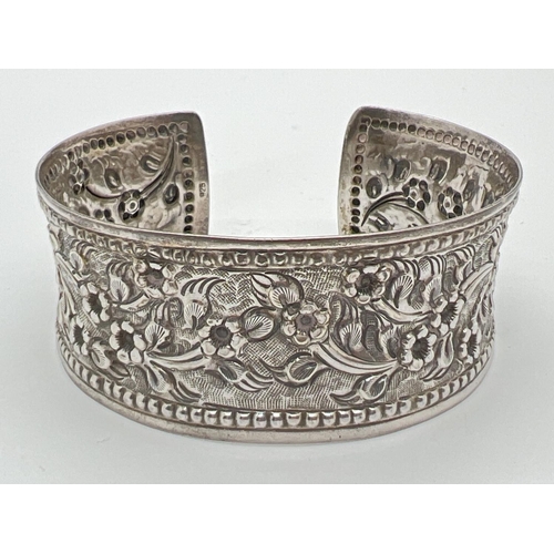 1074 - A vintage silver cuff style bangle decorated with floral design in relief. Bead detail to edges. Mar... 