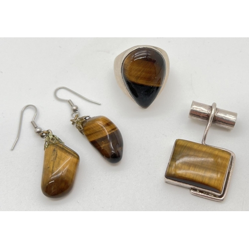 1080 - 2 pieces of modern design tigers eye set jewellery - a pendant and ring. Together with a pair of vin... 