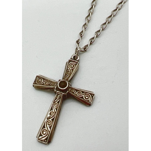 1081 - A vintage silver cross pendant with engraved scroll decoration and central clear stone. On a 24 inch... 