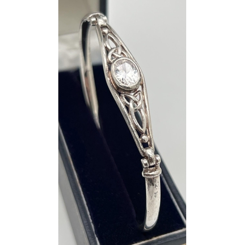 1084 - A silver Celtic design bangle set with a central oval cut clear quartz stone. Marked 925 to inside. ... 