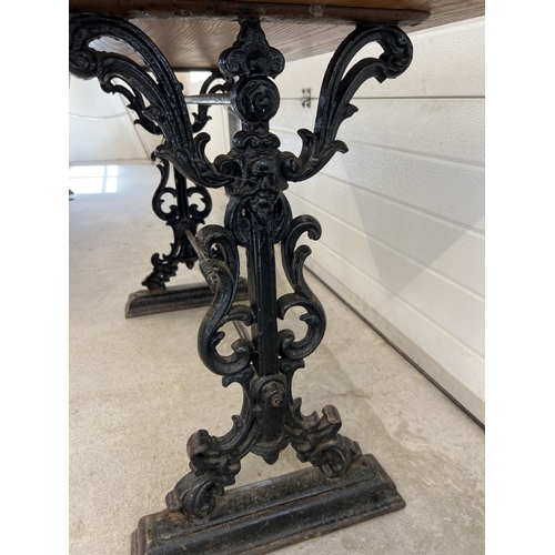 1348 - A vintage wooden topped table with cast iron base. Painted black cast iron legs with scroll, floral ... 