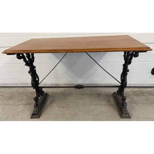 1349 - A vintage wooden topped table with cast iron base. Painted black cast iron decorative legs with scro... 