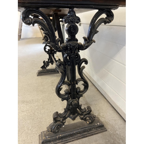 1349 - A vintage wooden topped table with cast iron base. Painted black cast iron decorative legs with scro... 