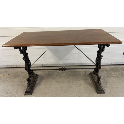 1350 - A vintage dark wood topped table with cast iron base. Painted black cast iron legs with floral, scro... 