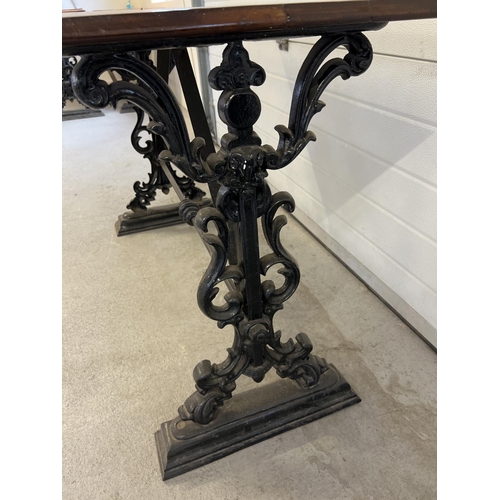 1350 - A vintage dark wood topped table with cast iron base. Painted black cast iron legs with floral, scro... 