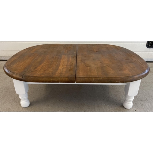 1354 - A low pine coffee table with varnish finish top and painted white base and legs. Approx. 31 x 105 x ... 