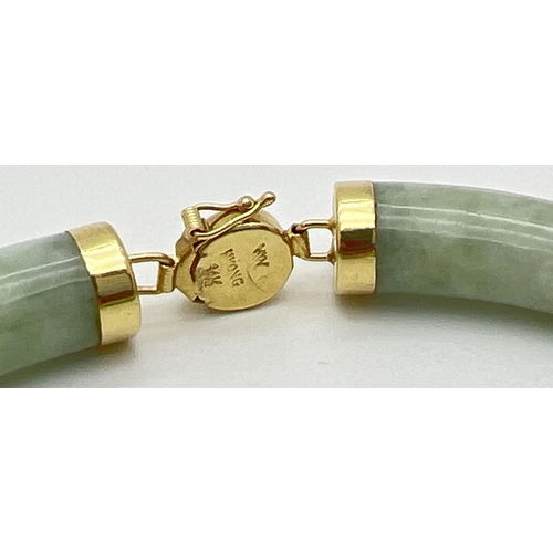 49 - A 14ct gold and pale green jade bracelet. Long curved jade beads with capped ends and alternating go... 