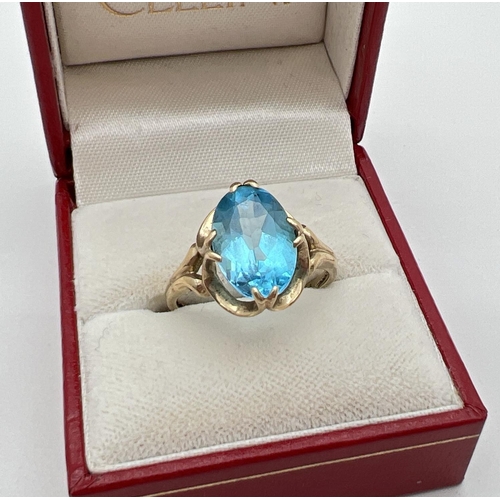 60 - A 9ct gold dress ring set with a large oval cut Swiss blue topaz in a decorative mount. Full hallmar... 