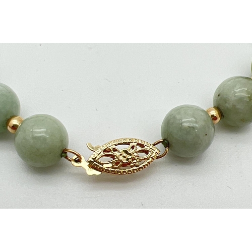 8 - A green jade and 14ct gold bead bracelet with pierced work fishhook clasp. Alternating round green j... 