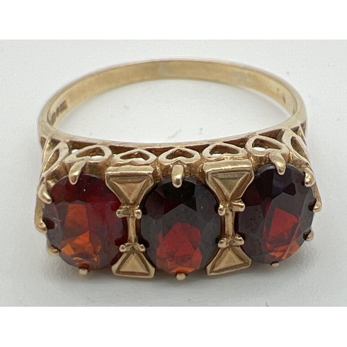 69 - A 9ct gold vintage style garnet set trilogy ring. Decorative high mount with heart design pierced wo... 