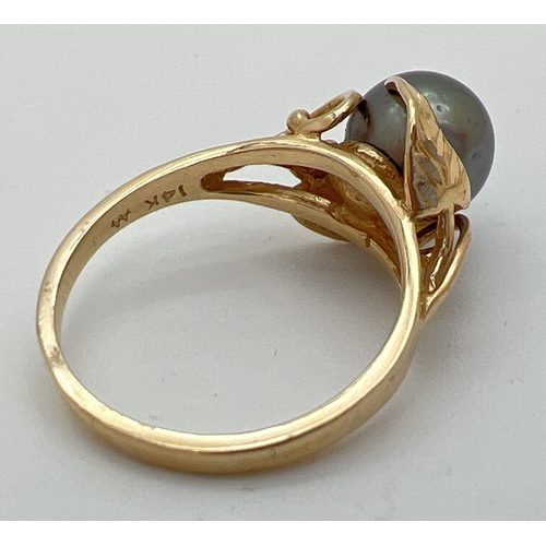 70 - A 14ct gold dress ring set with a large round gunmetal grey pearl. With leaf and vine design mount. ... 