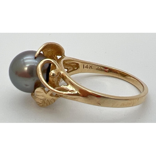 70 - A 14ct gold dress ring set with a large round gunmetal grey pearl. With leaf and vine design mount. ... 