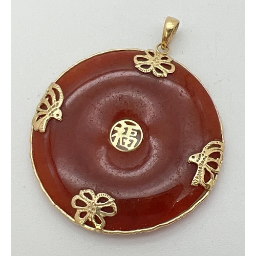 71 - A 14k gold and orange/brown jade pendant with floral overlay detail and Chinese character to centre ... 