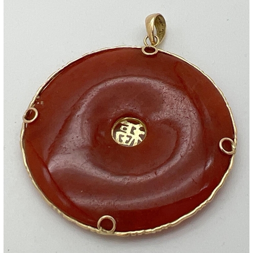 71 - A 14k gold and orange/brown jade pendant with floral overlay detail and Chinese character to centre ... 