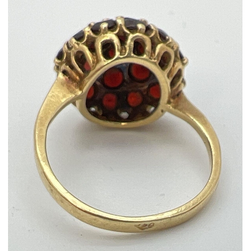 74 - A vintage 18k gold garnet set cluster style ring. Central garnet surrounded by 6 round cut garnets a... 