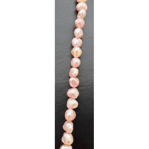 75 - A 35 inch string of pale pink freshwater pearls in varying shapes and lustres.