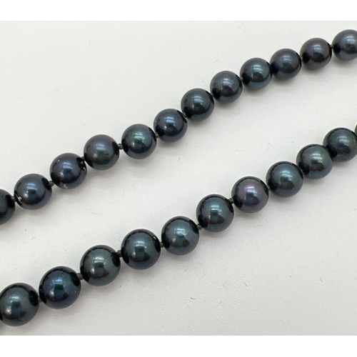 76 - An 18 inch knotted black pearl necklace with 9ct gold ball push clasp. Gold marks to clasp.