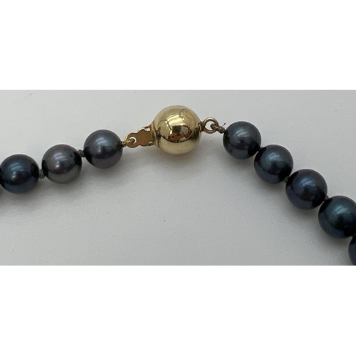 76 - An 18 inch knotted black pearl necklace with 9ct gold ball push clasp. Gold marks to clasp.