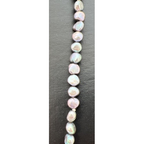 82 - A 35 inch string of blue freshwater pearls in varying shapes and lustres.