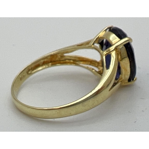 89 - A 14K gold dress ring with a large oval cut claw set dark blue tanzanite stone. Gold marks to inside... 