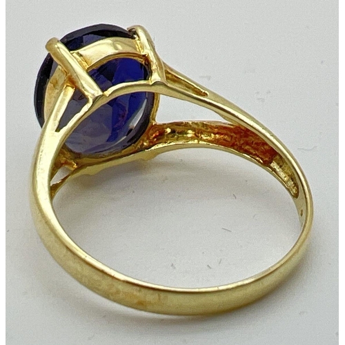 89 - A 14K gold dress ring with a large oval cut claw set dark blue tanzanite stone. Gold marks to inside... 