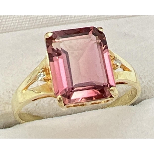 39 - A 14K gold ring set with an emerald cut blush tourmaline and two small round cut diamonds to each sh... 