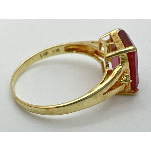 39 - A 14K gold ring set with an emerald cut blush tourmaline and two small round cut diamonds to each sh... 