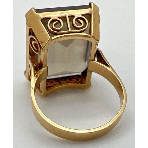 31 - An 18K gold cocktail ring set with a large emerald cut smoked quartz stone. In claw set mount with p... 