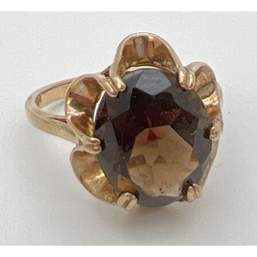 100 - A vintage 9ct gold smoked quartz dress ring set in a fluted style mount. Central oval stone approx. ... 