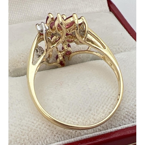 22 - A 14ct gold ruby and diamond set dress ring in a flower design mount. 12 marquise cut small rubies t... 