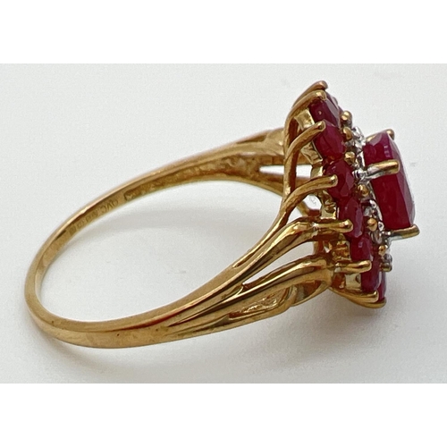 10 - A 9ct gold cluster style ruby and diamond dress ring with scroll detail to shoulders. Central oval c... 