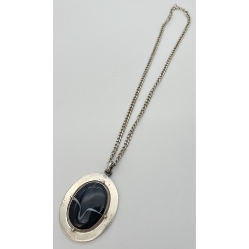 1133 - A large white metal pendant set with an oval black agate stone, on a 20