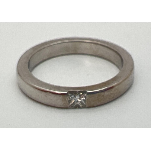 1136 - A 18k white gold band ring set with a square cut 0.10ct diamond. Full hallmarks to inside of band. R... 