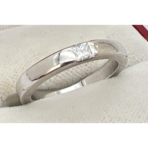 1136 - A 18k white gold band ring set with a square cut 0.10ct diamond. Full hallmarks to inside of band. R... 