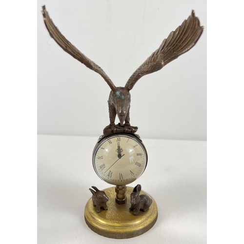 1213 - An ornamental brass ball clock with eagle shaped finial and rabbit figures to base. With wind up mec... 