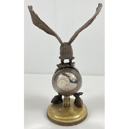 1213 - An ornamental brass ball clock with eagle shaped finial and rabbit figures to base. With wind up mec... 