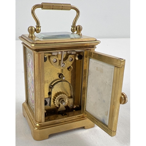 1206 - A miniature brass cased carriage clock with hand painted porcelain panels. Bevel edged glass, gilt d... 